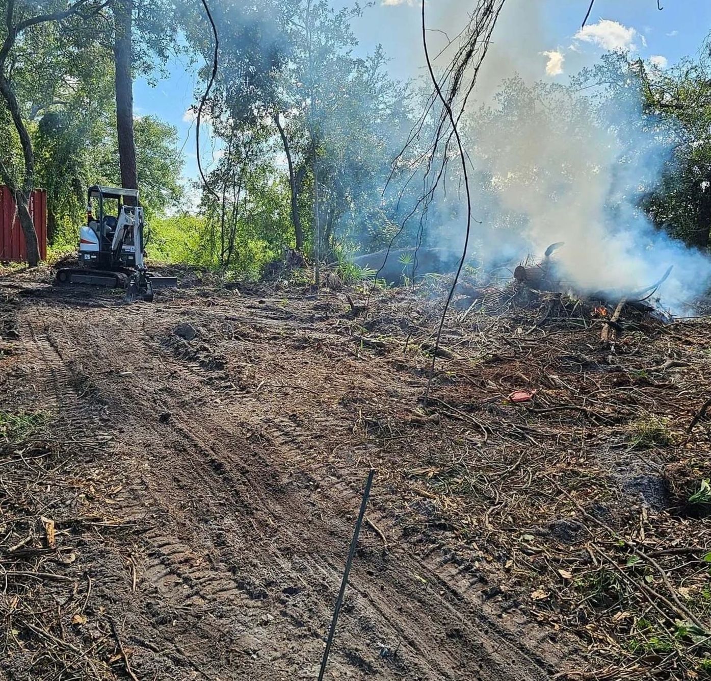 A bulldozer is standing in the middle of a forest with smoke coming out of it.