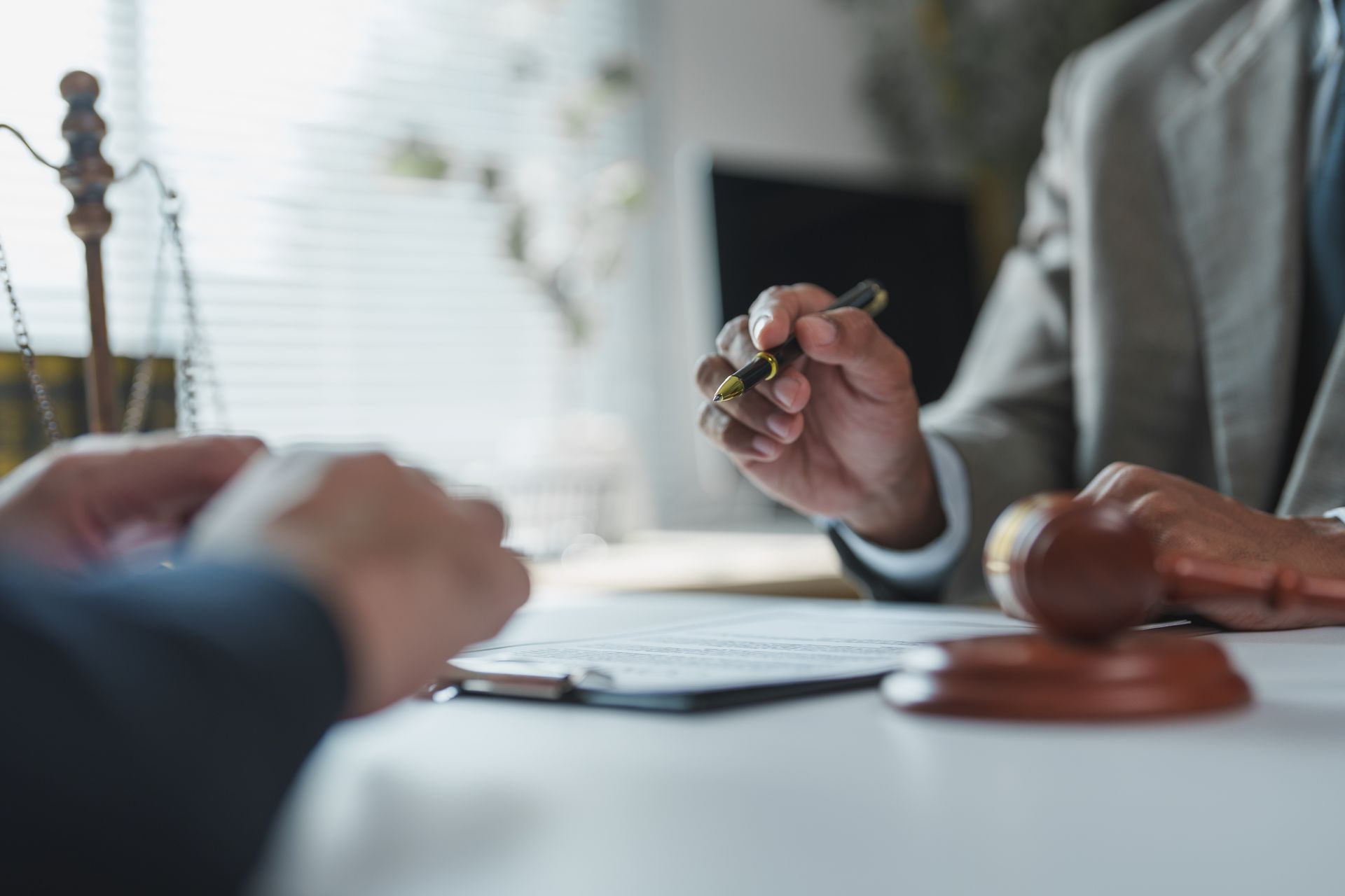 Client signing documents with a lawyer, gavel on desk in legal office. Client signing documents with a lawyer, gavel on desk in legal office.