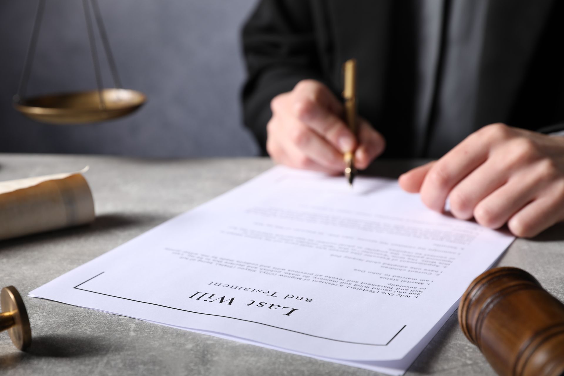 An unrecognized person signing last will and testament on a gray table.
