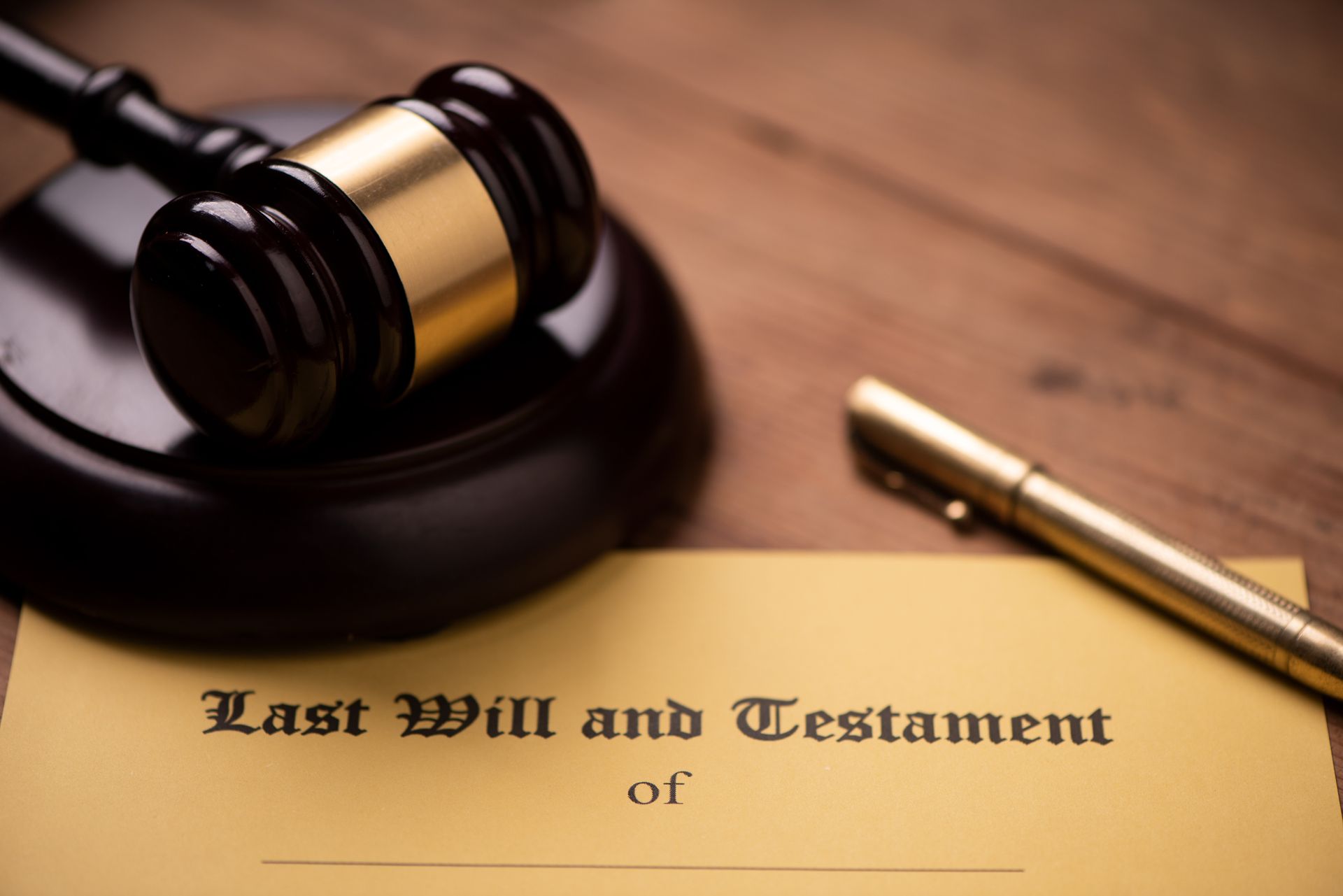 Last will and testament form with a gavel and pen on a wooden desk. Last will and testament form with a gavel and pen on a wooden desk.