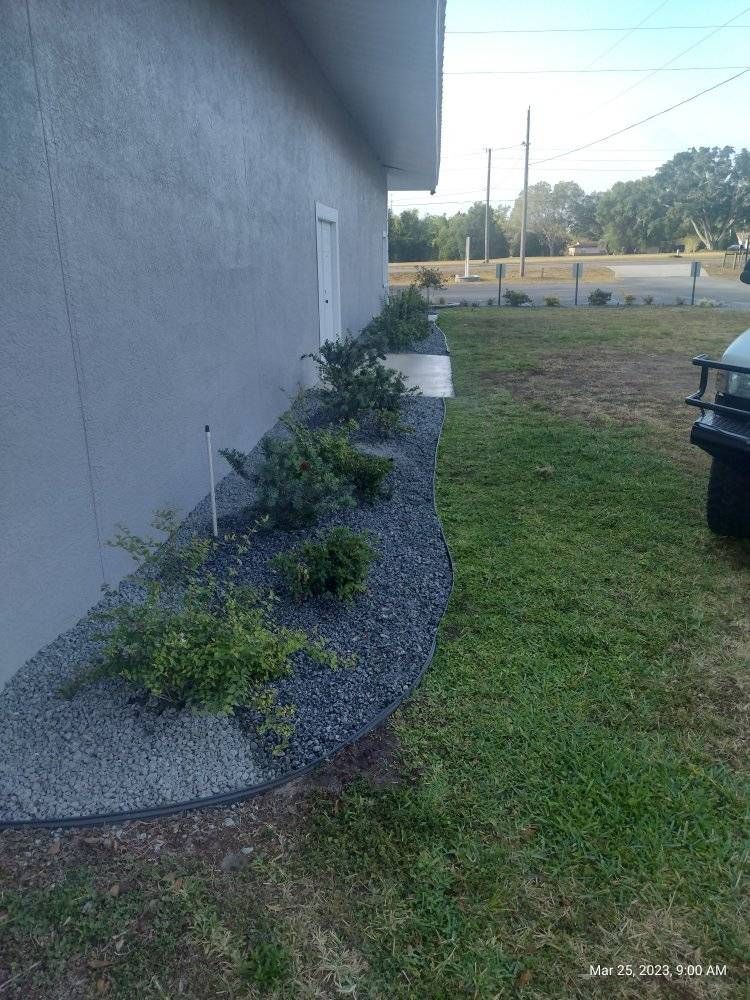 A building with a rock bed and small green plants next to grass.