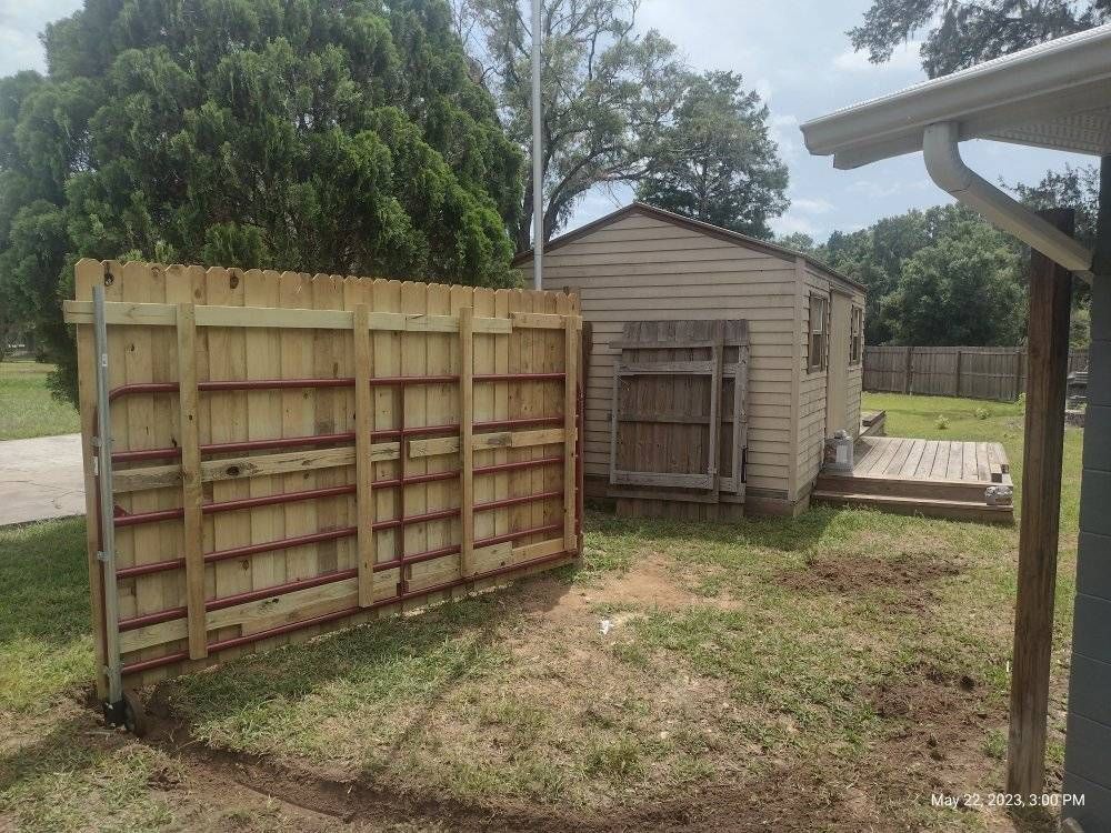 Wooden fence next to a small wooden shed with a small wooden deck and green lawn.