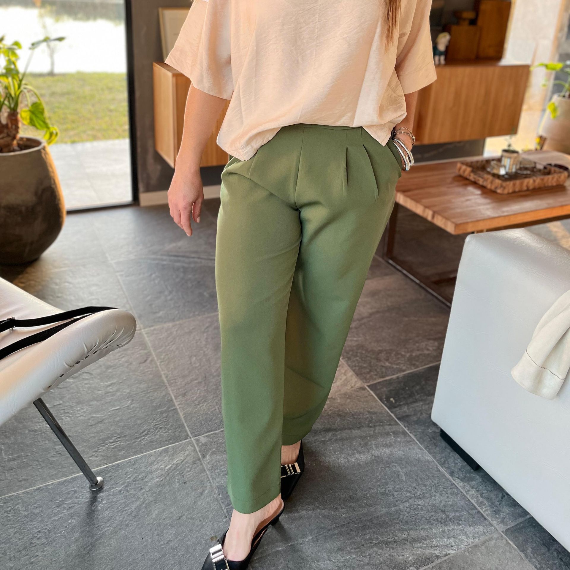 Mujer con top color crema y pantalón verde, en interior.