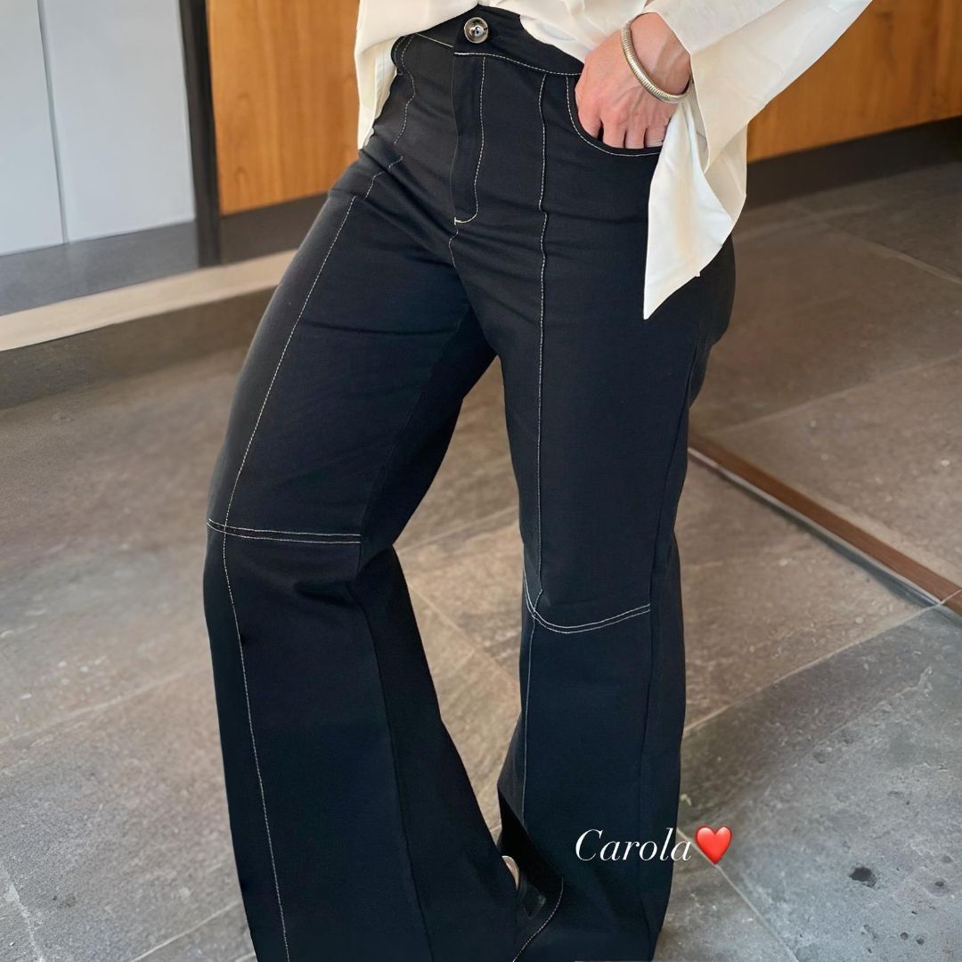 Persona que viste pantalón negro con costuras blancas y blusa blanca.