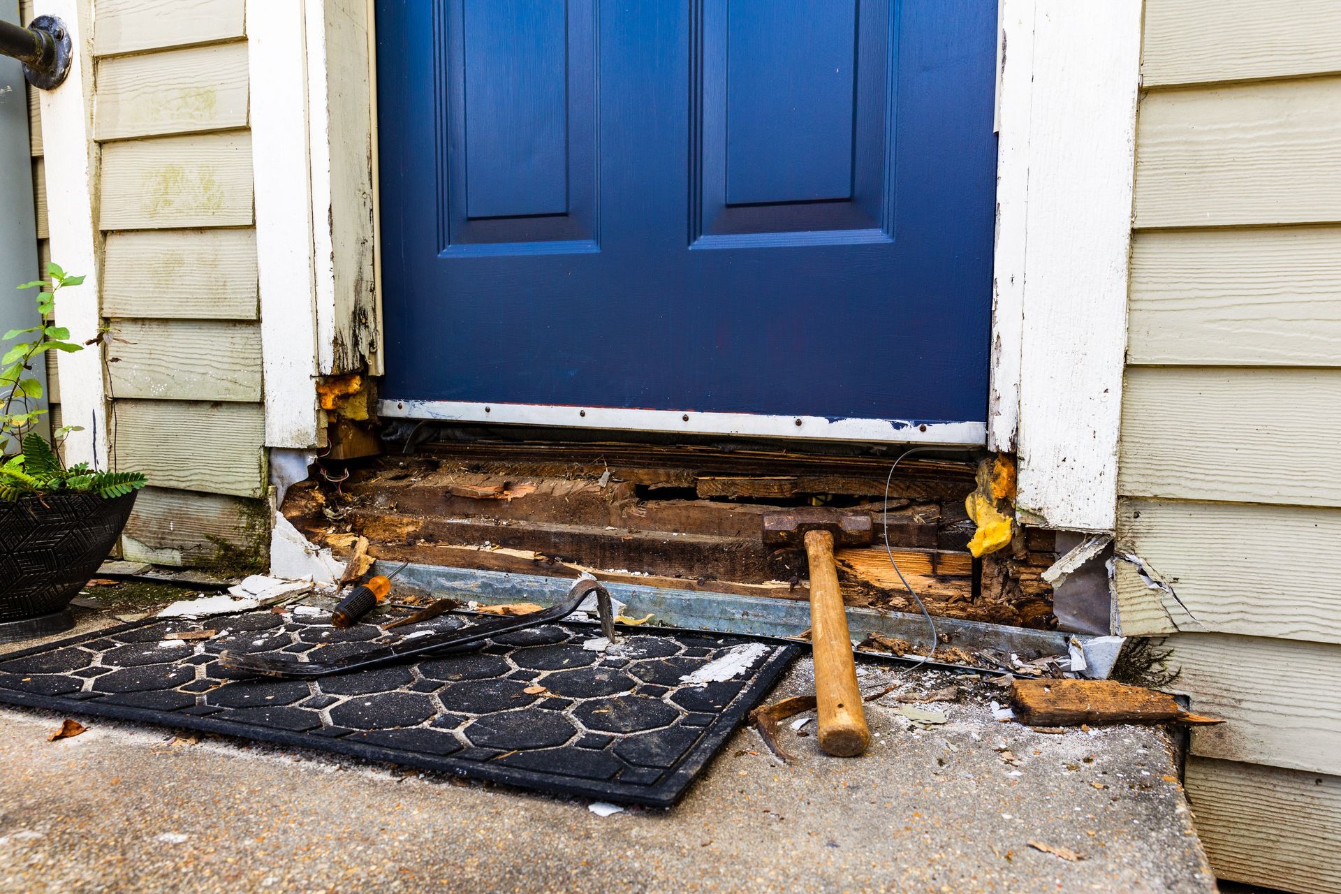 A blue door is being repaired on the side of a house.