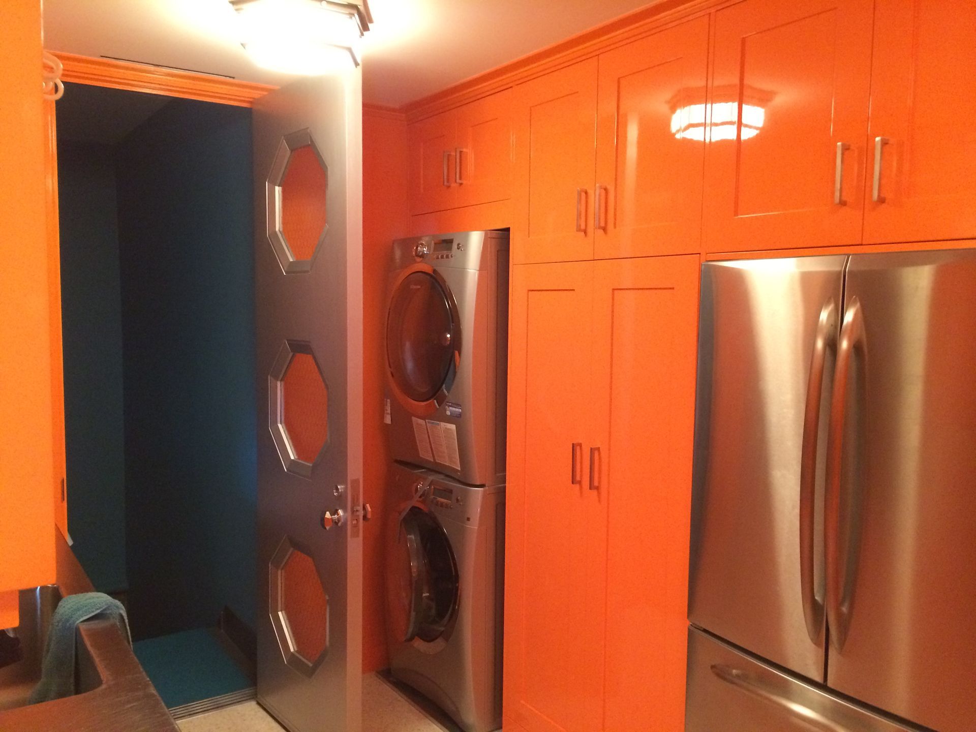 A laundry room with orange cabinets and stainless steel appliances