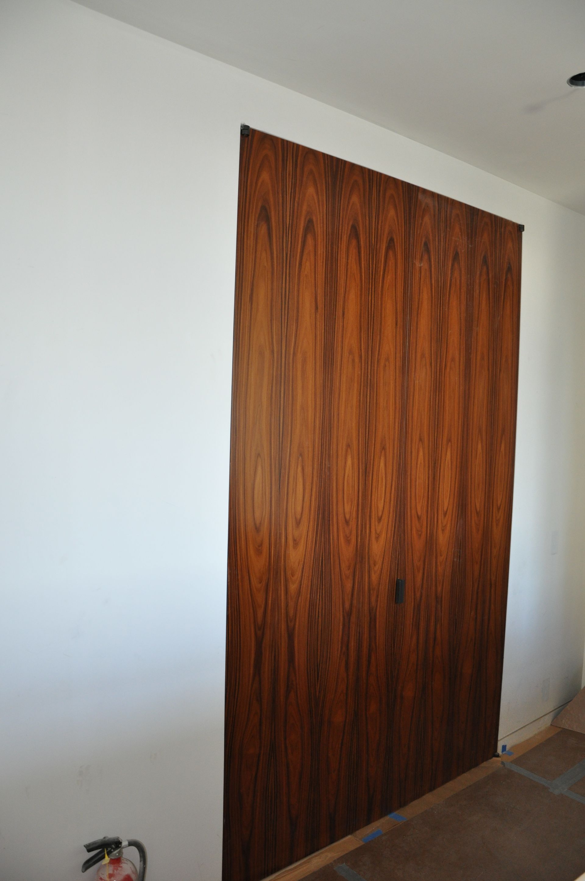 A wooden door is hanging on a white wall in a room.