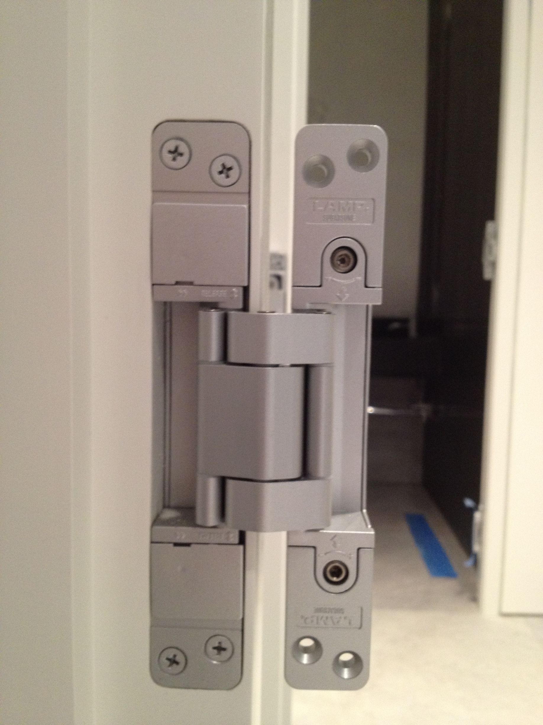 A close up of a door hinge on a white door