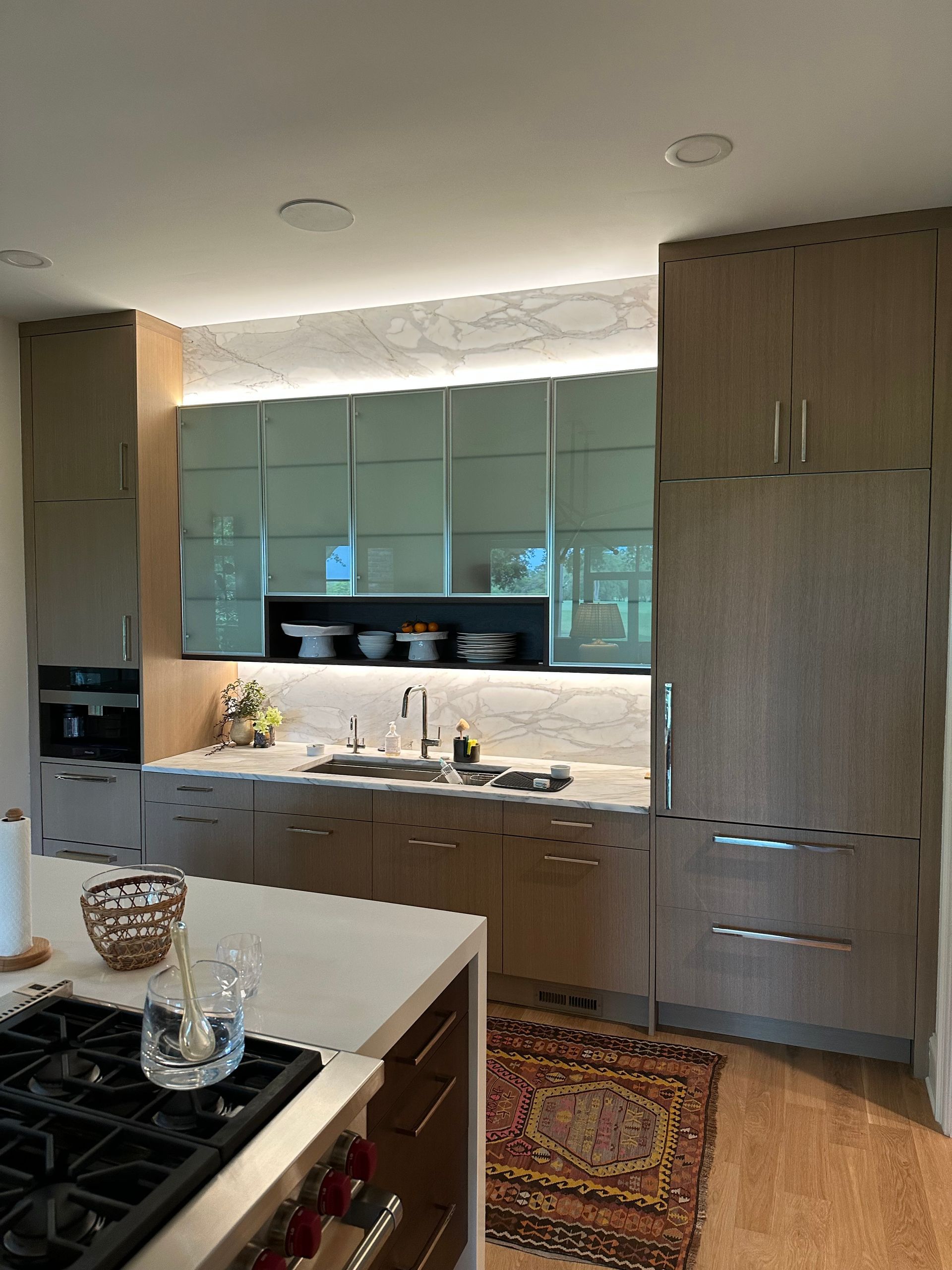 A kitchen with a stove , sink , refrigerator and cabinets.