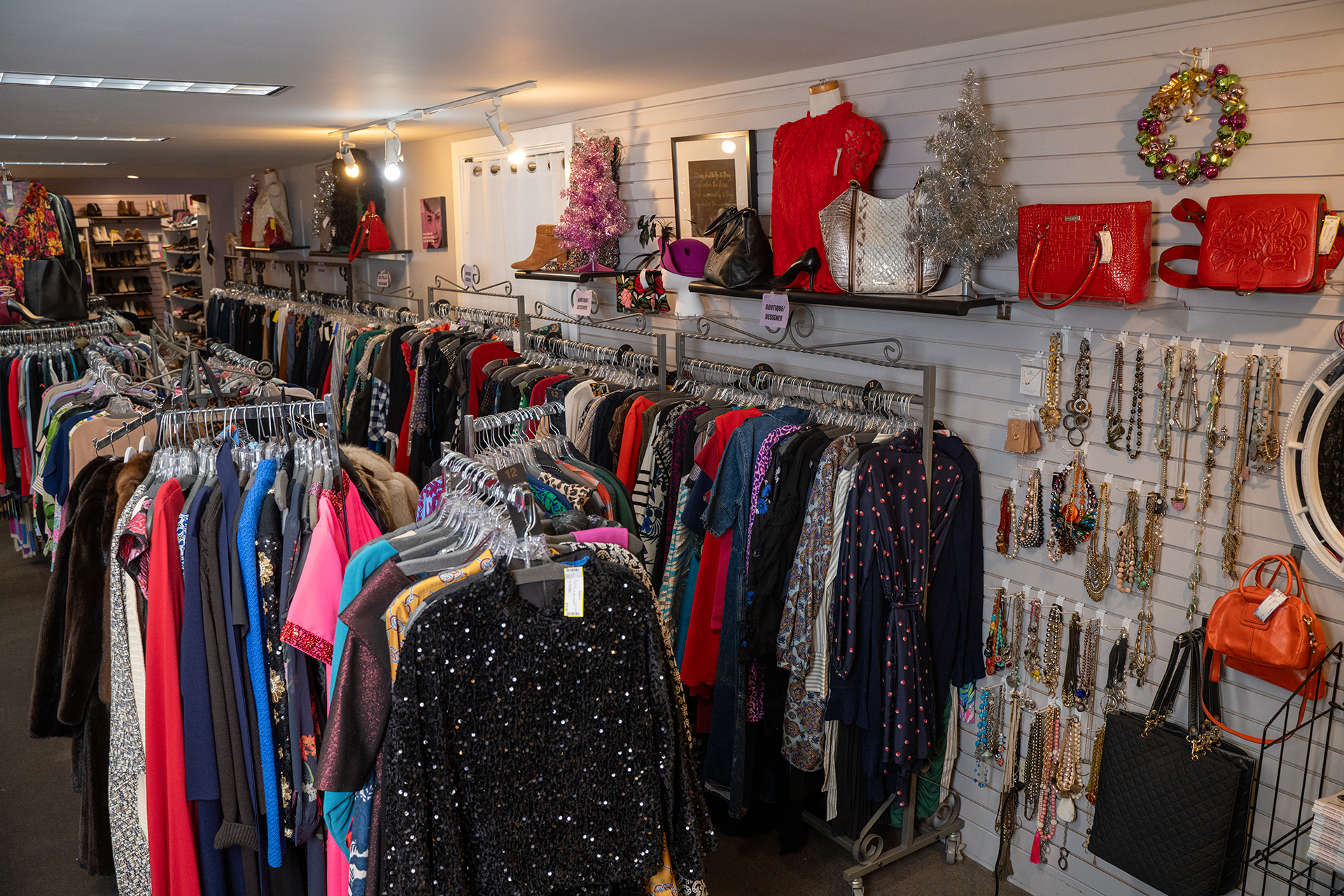 Two women in stylish fall outfits with boots and handbags standing by a wall.