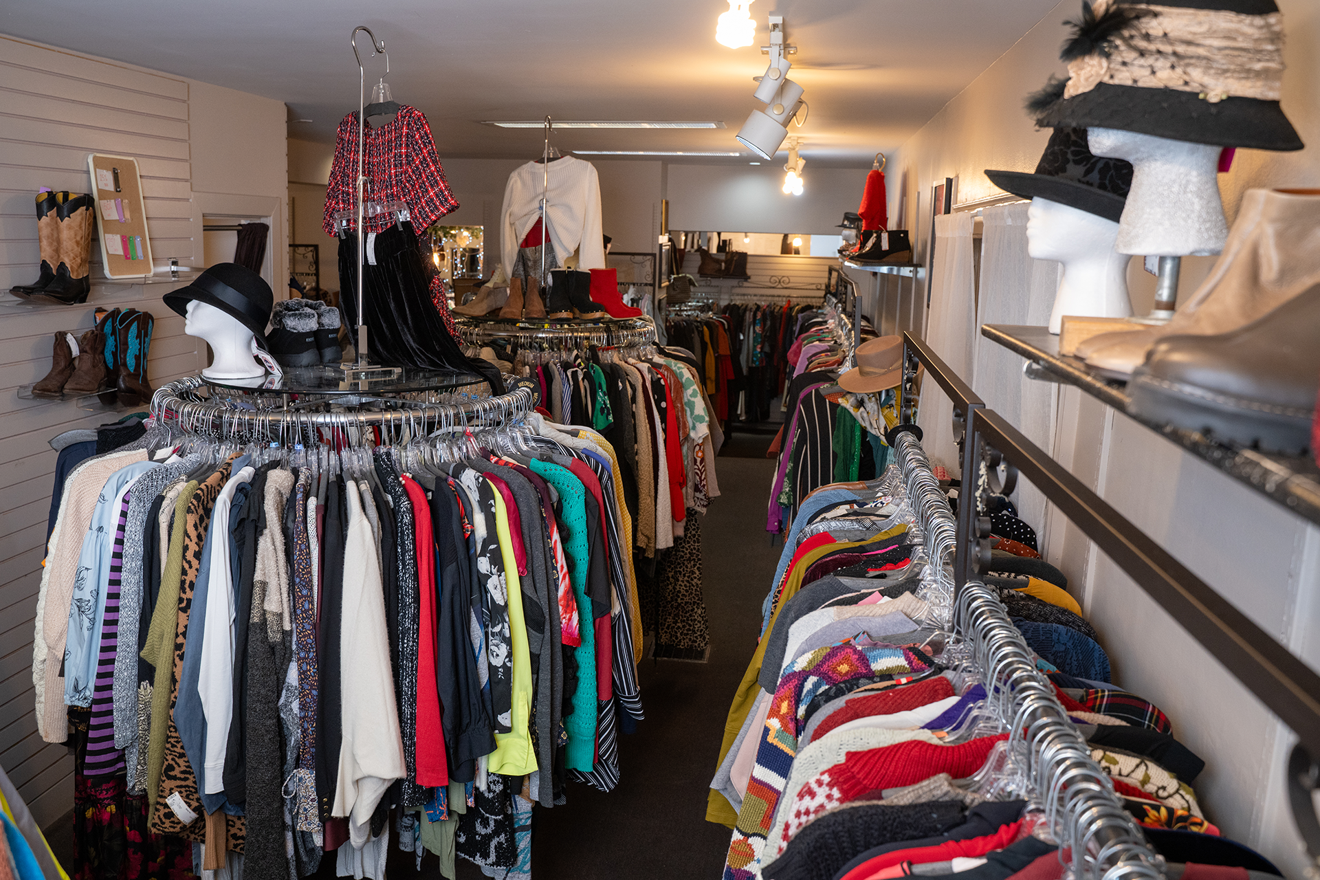 Woman in yellow jacket, rust scarf, and jeans smiles at camera. Against a blue background.
