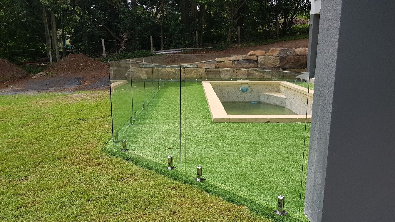 A Glass Fence Surrounds a Swimming Pool in A Backyard — Tuggerah Lakes Glass In Tumbi Umbi, NSW