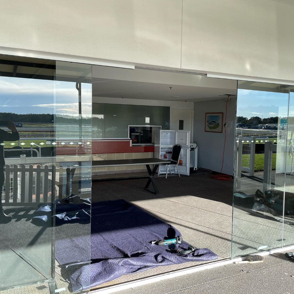 A room with sliding glass doors leading to a balcony. — Tuggerah Lakes Glass In The Entrance, NSW