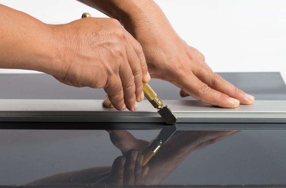 A Person is Cutting a Piece of Glass With a Glass Cutter — Tuggerah Lakes Glass In Wyong, NSW
