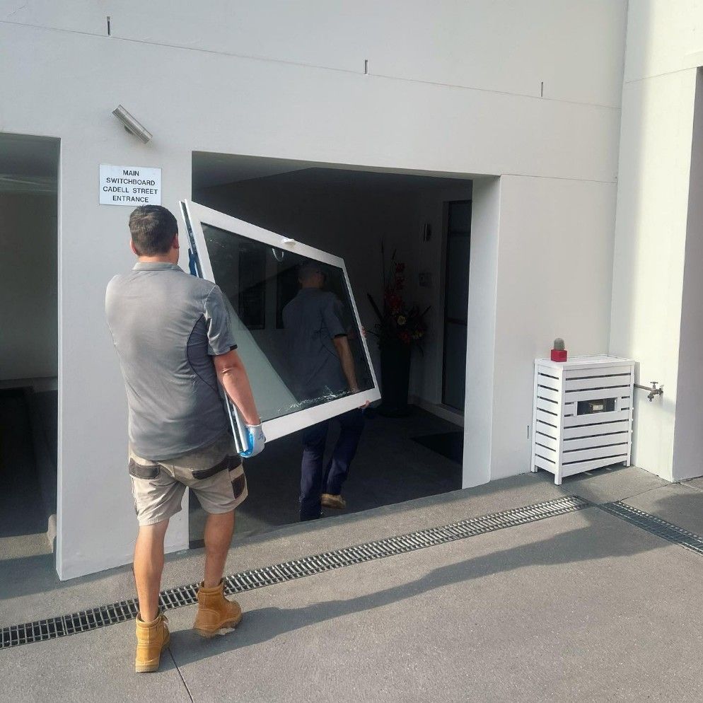 Man Carrying a Large Window Through an Entrance — Tuggerah Lakes Glass In Tumbi Umbi, NSW