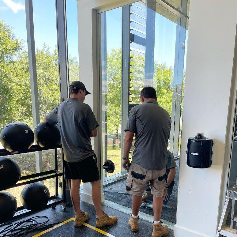 Two Men Installing Glass Window in a Gym — Tuggerah Lakes Glass In Tumbi Umbi, NSW