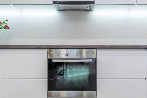 A Stainless Steel Oven is Sitting Under a Hood in a Kitchen — Tuggerah Lakes Glass In Tumbi Umbi, NSW