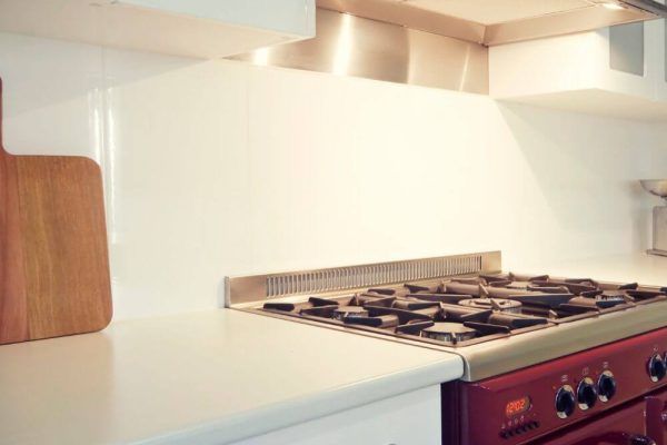 A Kitchen With a Red Stove Top Oven and a Wooden Cutting Board on the Counter — Tuggerah Lakes Glass In Tumbi Umbi, NSW