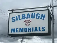 Sign for Silbaugh Memorials with white background, blue text, and a red and white logo.