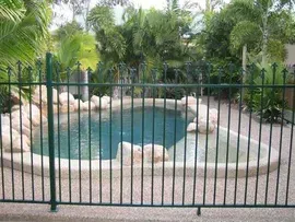 A Swimming Pool With A Green Fence Around It — Fencing Around Town Townsville in Garbutt, QLD