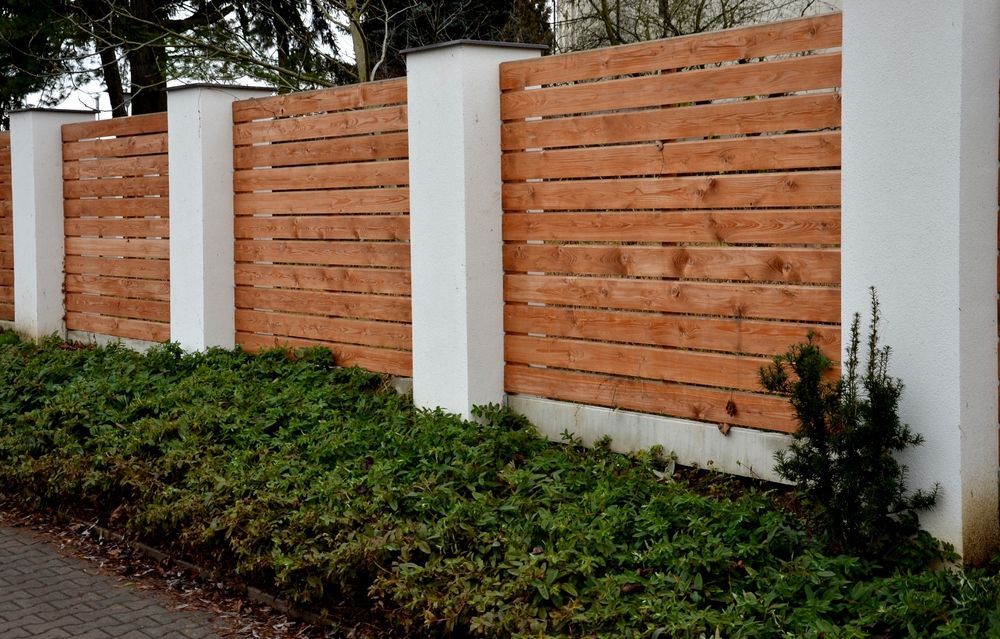A Wooden Gate is Sitting in Front of a White Building — Fencing Around Town Townsville in Garbutt, QLD