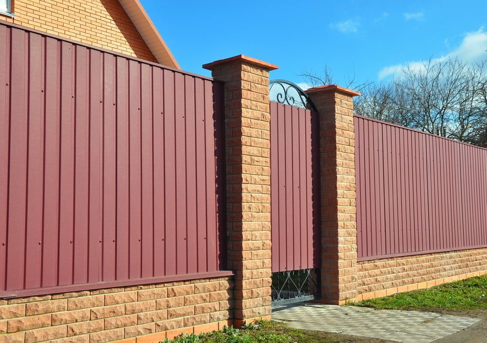 A Brick Fence With a Metal Fence and a Gate in Front of a Brick House — Fencing Around Town Townsville in Garbutt, QLD