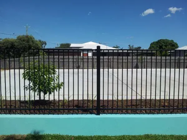 A Black Metal Fence with A Blue Wall and A Tree in The Foreground  — Fencing Around Town Townsville in Garbutt, QLD