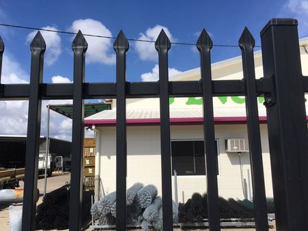 A Black Metal Fence Surrounds a Lush Green Yard — Fencing Around Town Townsville in Garbutt, QLD