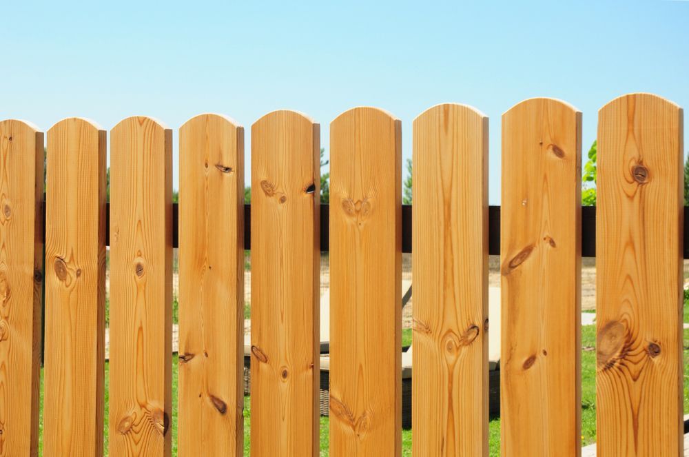 Wooden Fence With Vertical Planks And Rounded Tops
