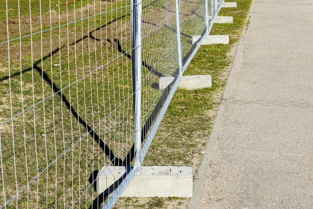 A Fence is Sitting on the Side of a Road Next to a Grassy Field — Fencing Around Town Townsville in Garbutt, QLD