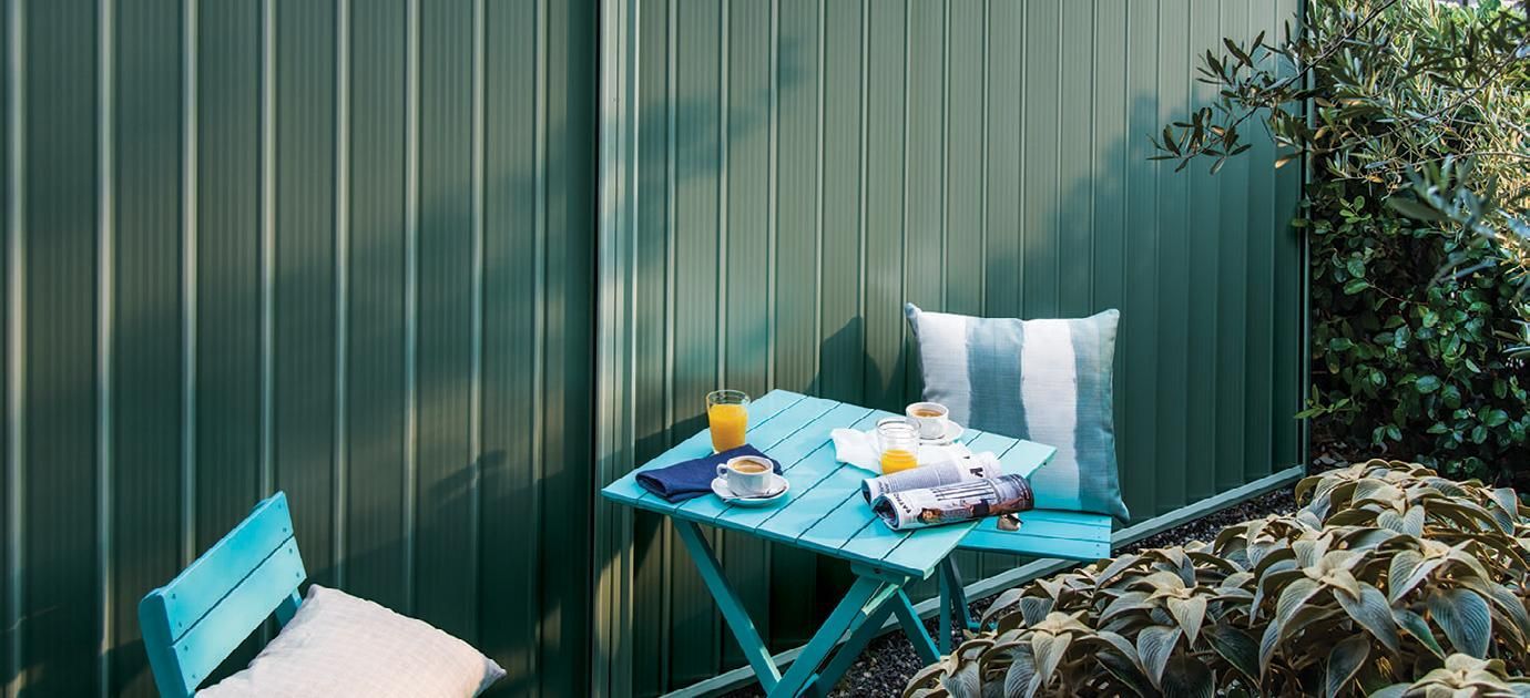 A Table and Chairs Are Sitting in Front of a Green Fence — Fencing Around Town Townsville in Garbutt, QLD