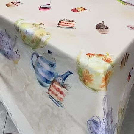 Un tavolo ricoperto da una tovaglia bianca stampata con illustrazioni in stile acquerello di teiere, torte e pasticcini di vario genere.