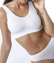 Una persona che indossa un reggiseno bralette bianco a tinta unita, senza cuciture e con scollo a U, abbinato a biancheria intima coordinata.