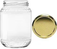 Un barattolo di vetro trasparente per il miele, con coperchio dorato coordinato e decorato con un motivo a nido d'ape.