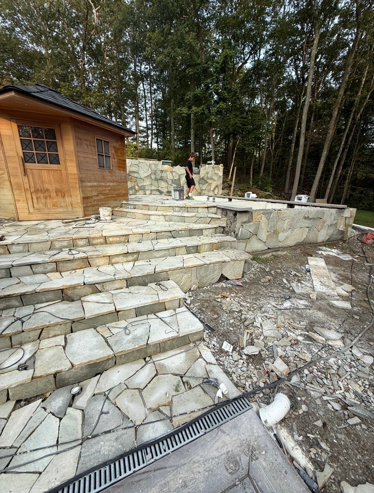 Spiral staircase with stainless steel handrail, speckled stone steps, looking down.
