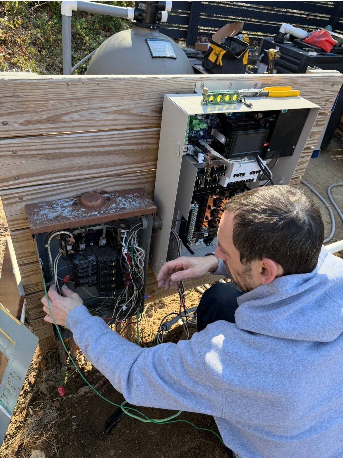 Stone steps and patio leading to an empty pool, with a stone wall and wooded background.