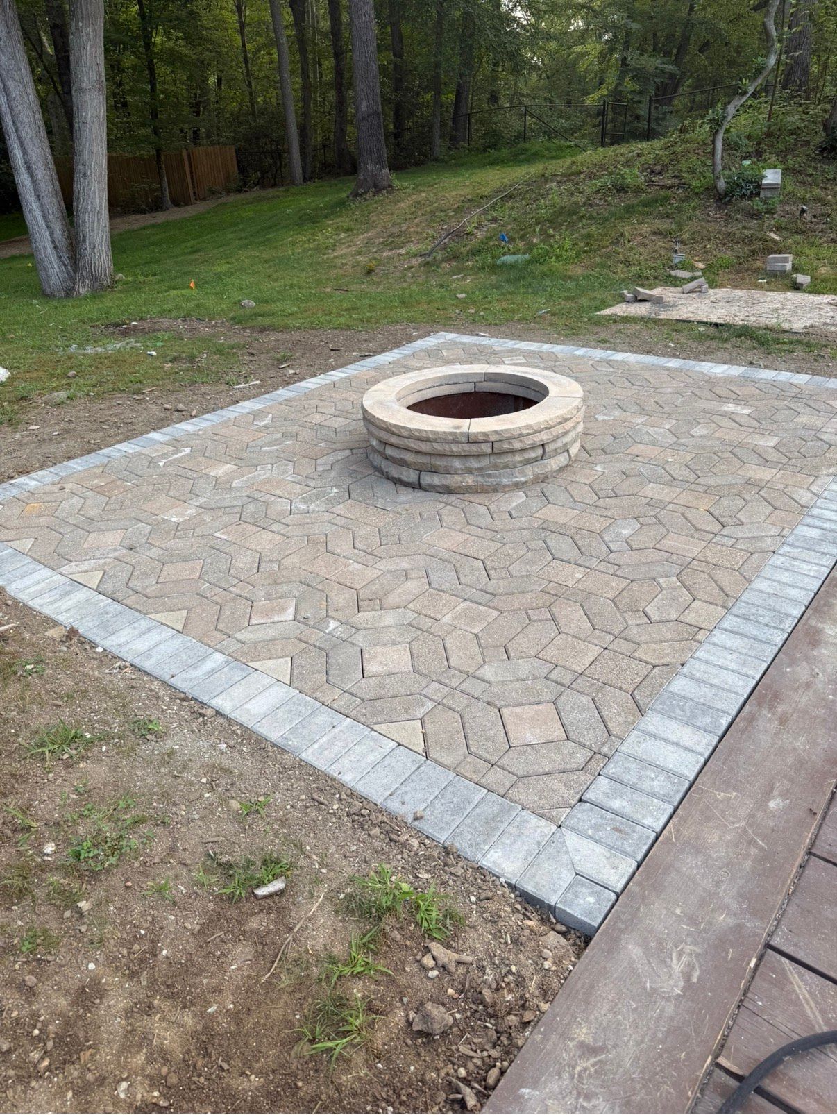 Person using a power grinder on stone wall, creating dust; wearing a cap and earbud.