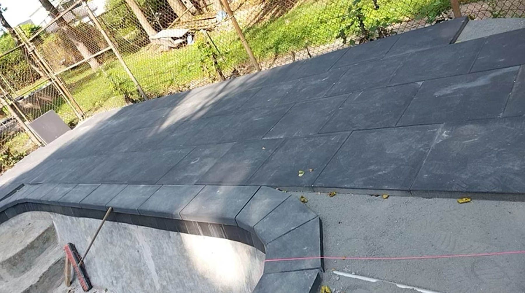 Rubber tiles covering a platform, with a curved edge and surrounding concrete.