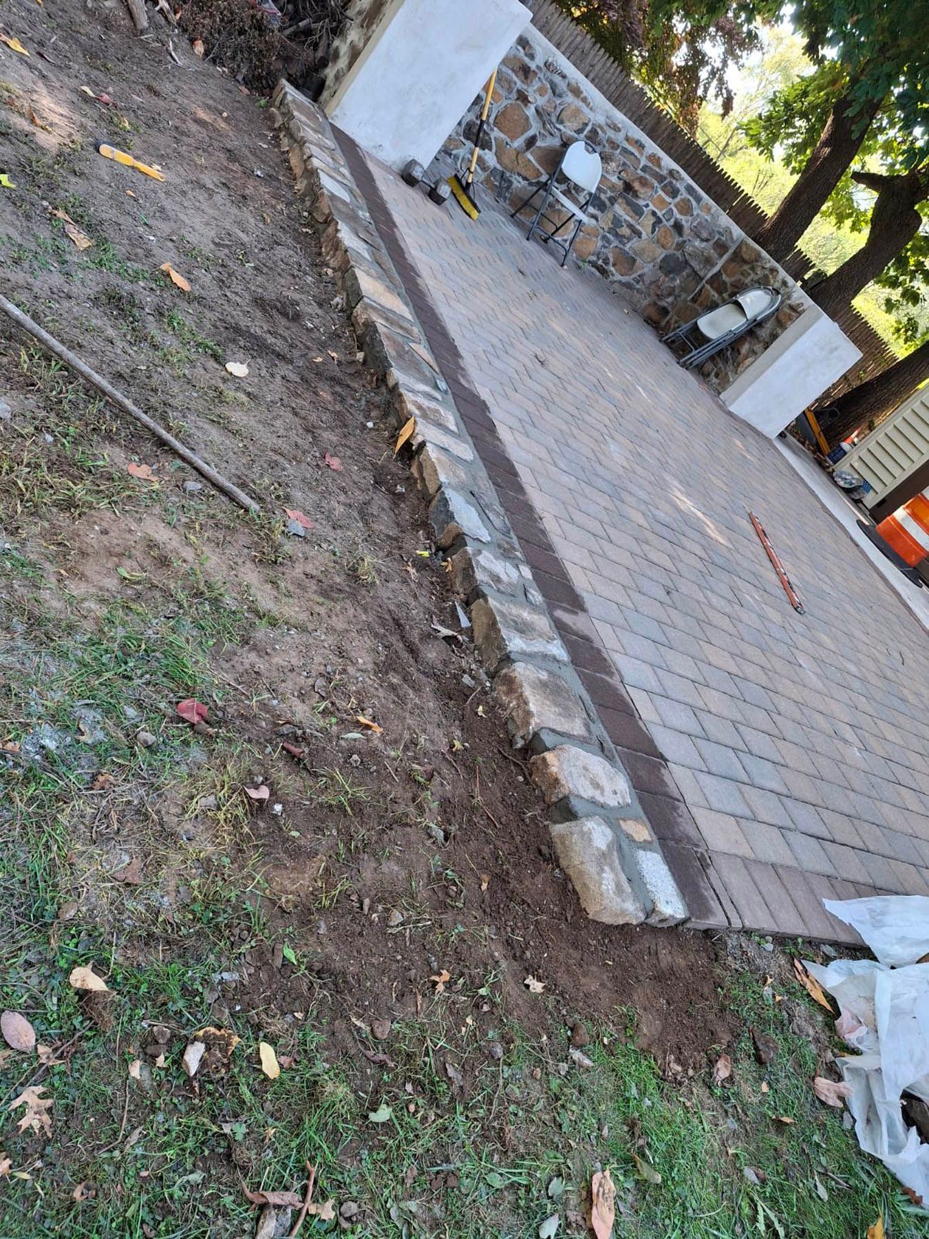Brick patio with a retaining wall on a sloped grassy area.