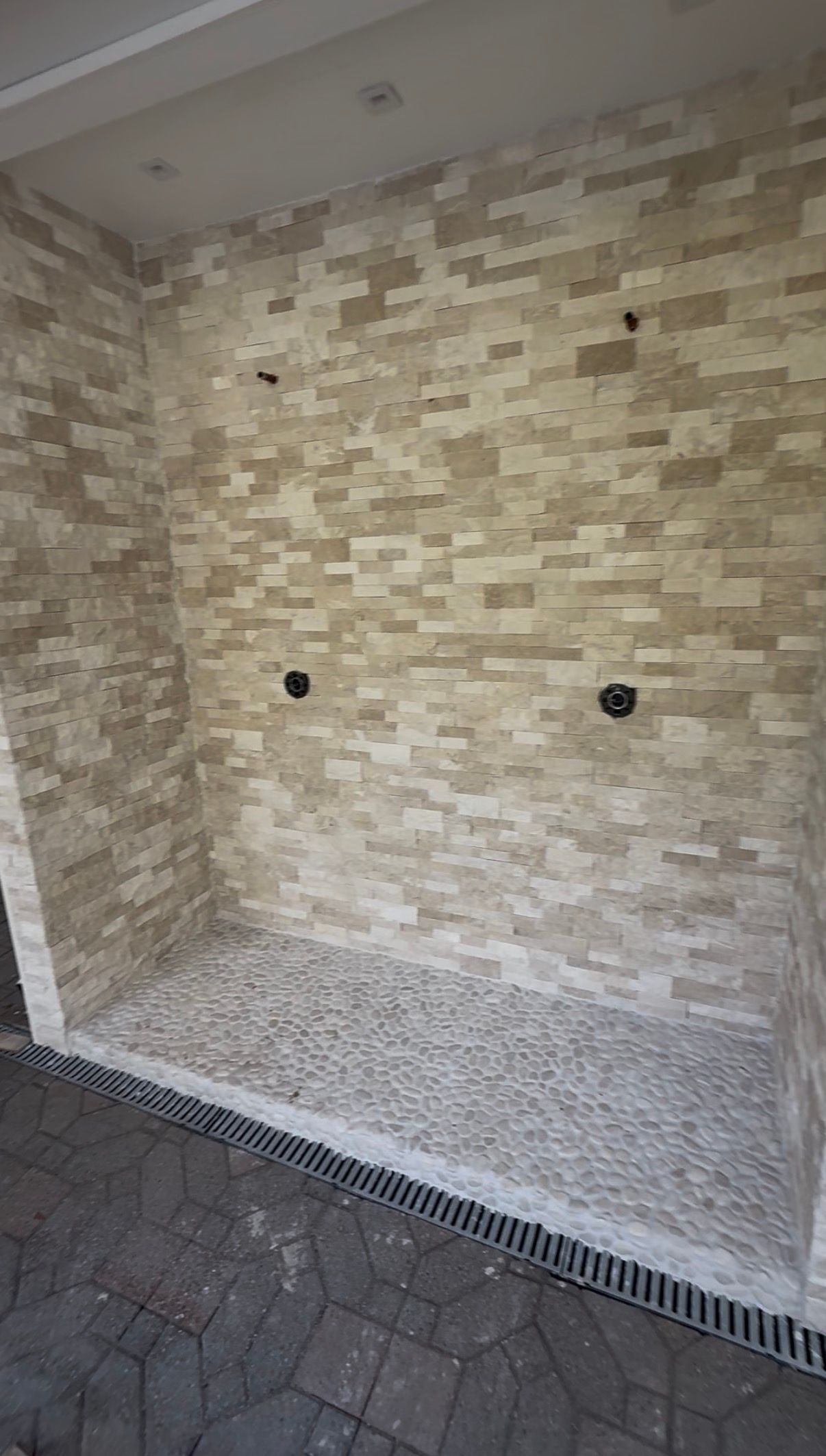 Interior view of a rectangular pool with stone-like tile walls and a pebble-covered bottom.