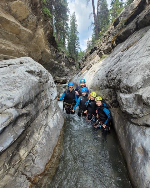 A group of people are standing in a river between two rocks.