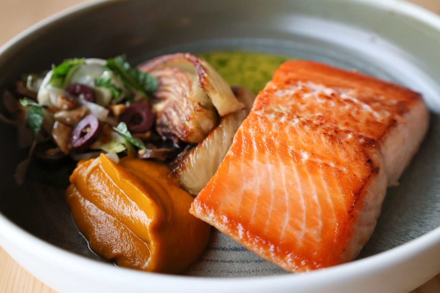 A close up of a plate of food with salmon and vegetables