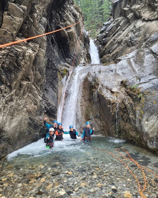 A group of people are standing in front of a waterfall.