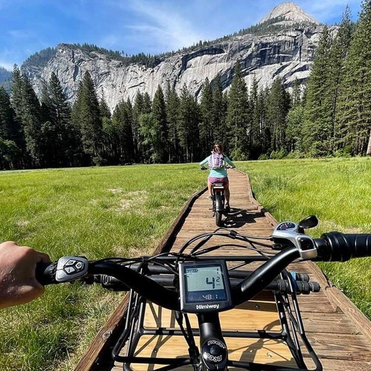 A person riding a bike on a boardwalk with a mountain in the background