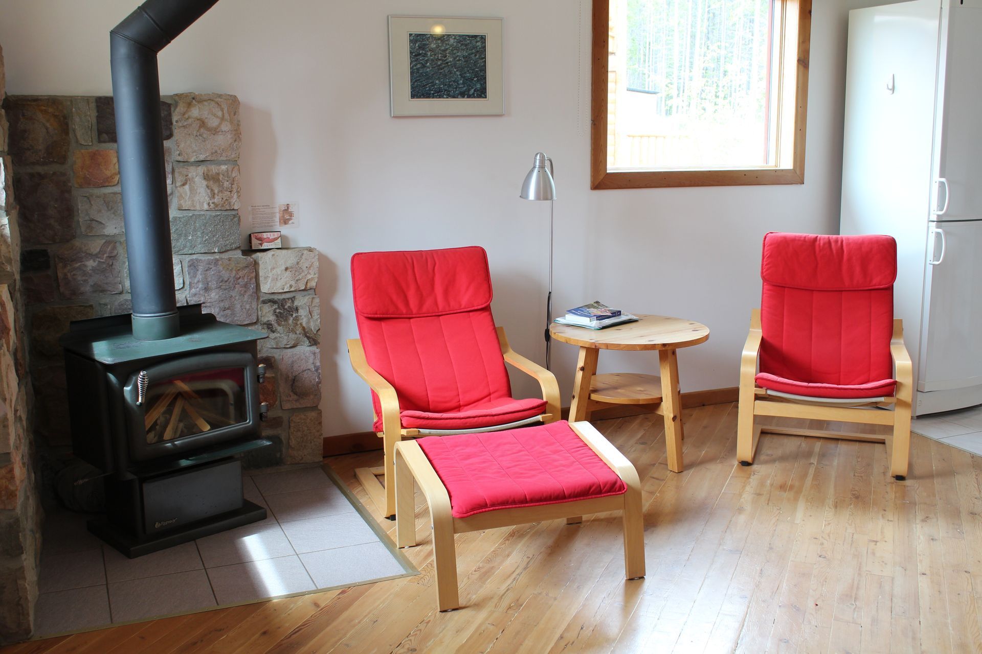 A living room with two red chairs and a wood stove