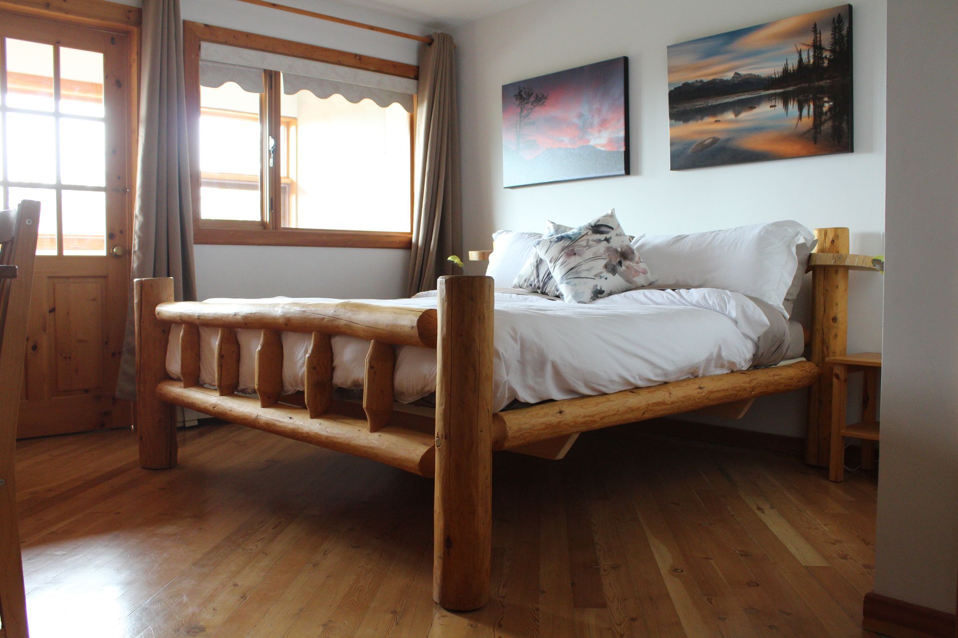 A bedroom with a wooden bed and two paintings on the wall