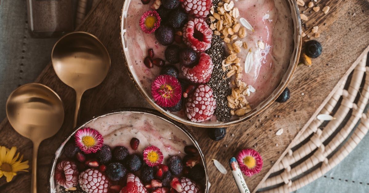 Two bowls of food with berries and nuts on a wooden table.