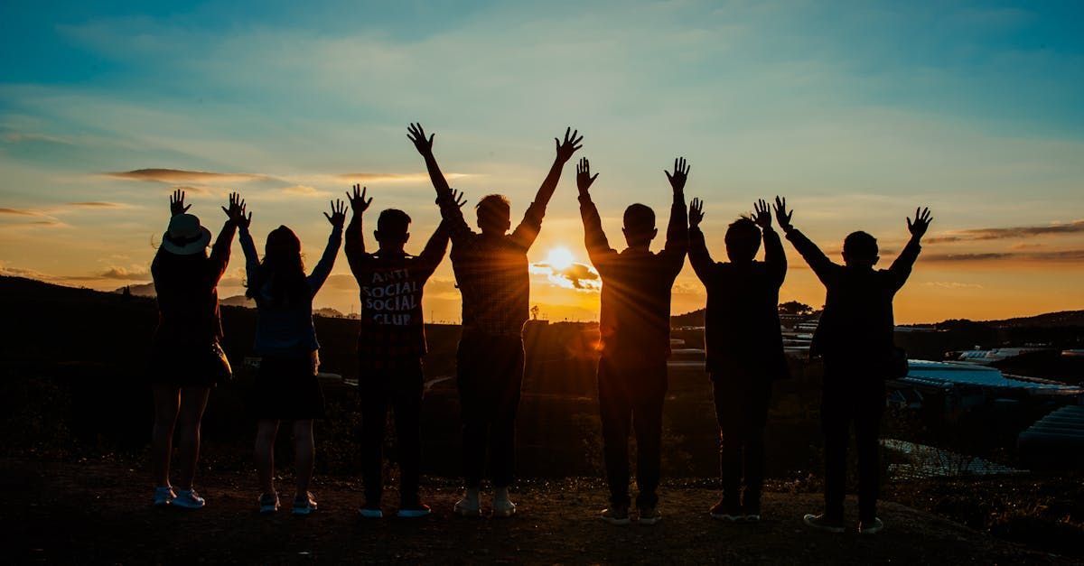 A group of people are standing in a field with their arms in the air.