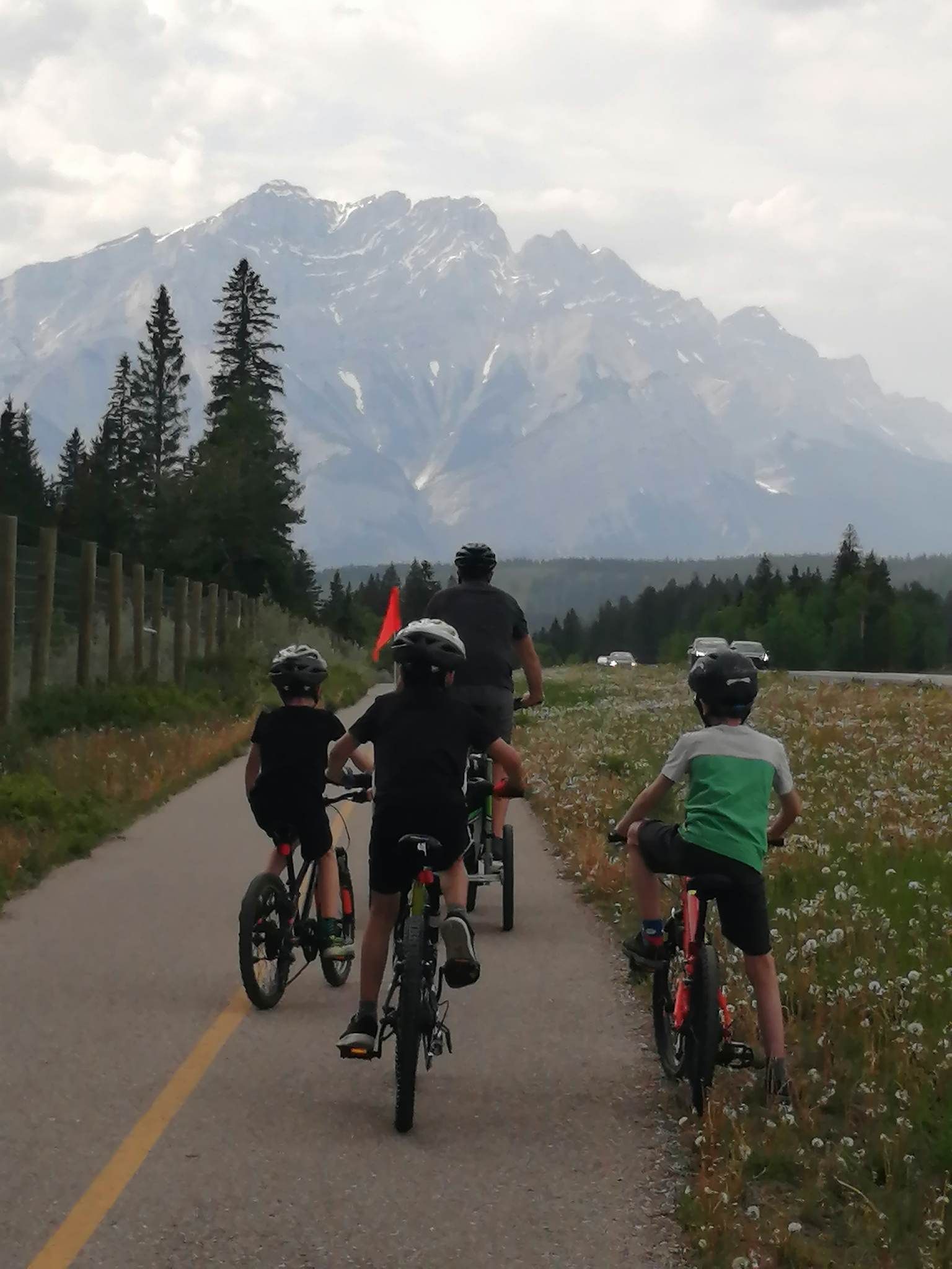 A group of people riding bikes down a road with mountains in the background