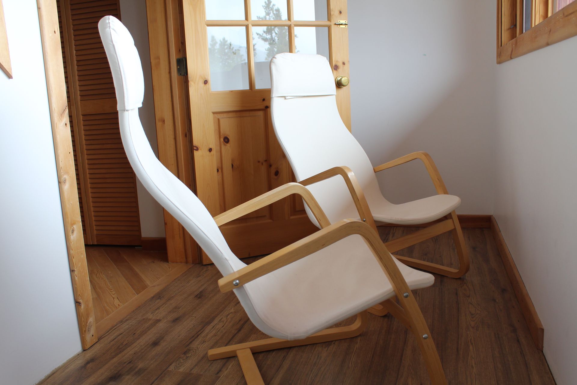 Two white rocking chairs are sitting next to each other in a room.